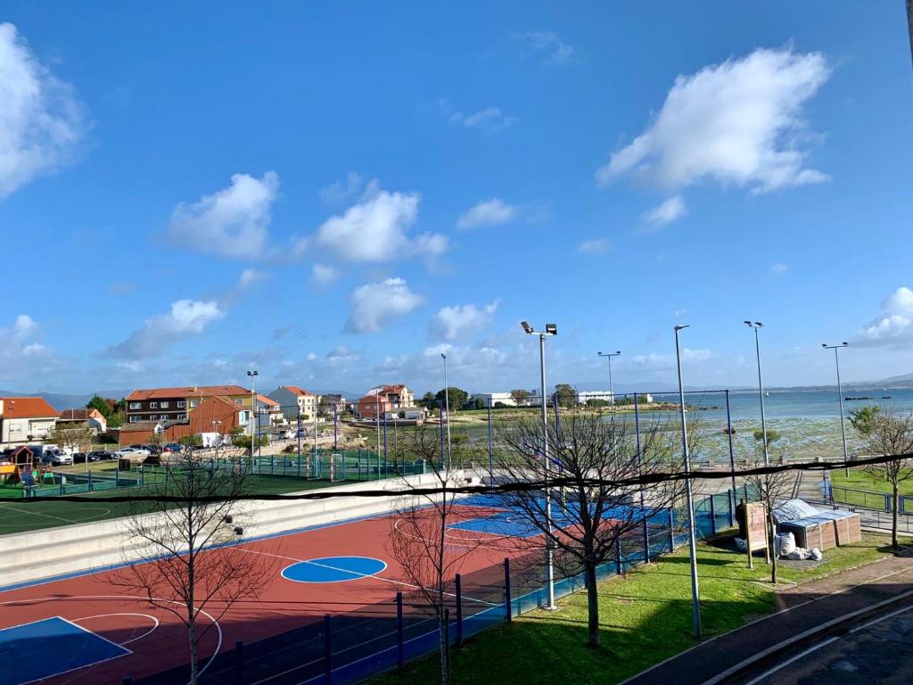 a tennis court next to a body of water at Apartamento en Terra do Porto con vistas in O Grove