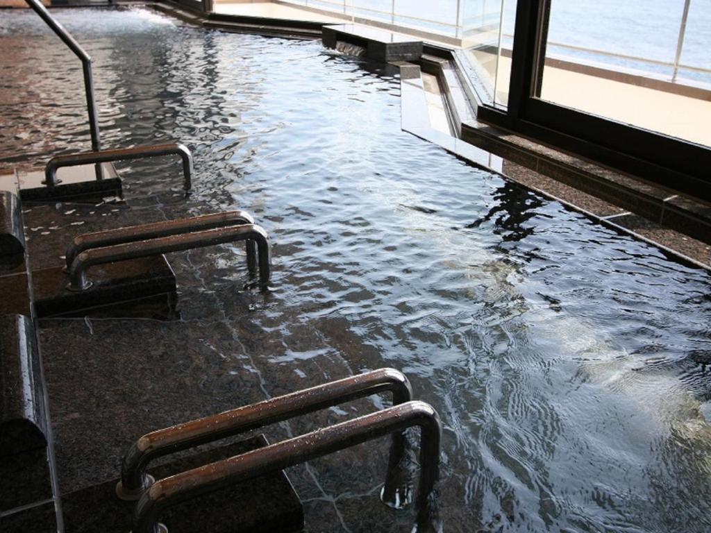 a pool of water with two benches in a building at Inatori Tokai Hotel Yuen in Higashiizu