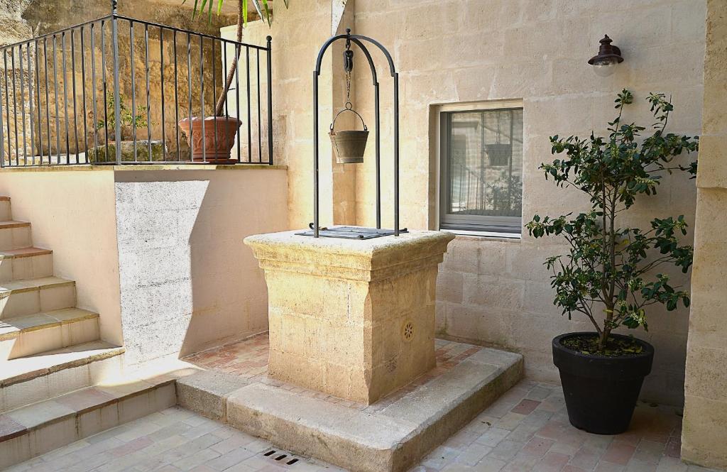 a stone fountain in the corner of a building with a plant at Il Belvedere in Matera