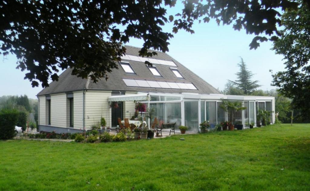 ein Haus mit Wintergarten auf einer Wiese in der Unterkunft Maison Magdala in Fourmies