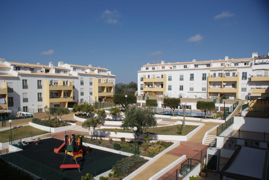 un complejo de apartamentos con un patio con parque infantil en Apartamento Felicidade en Almancil