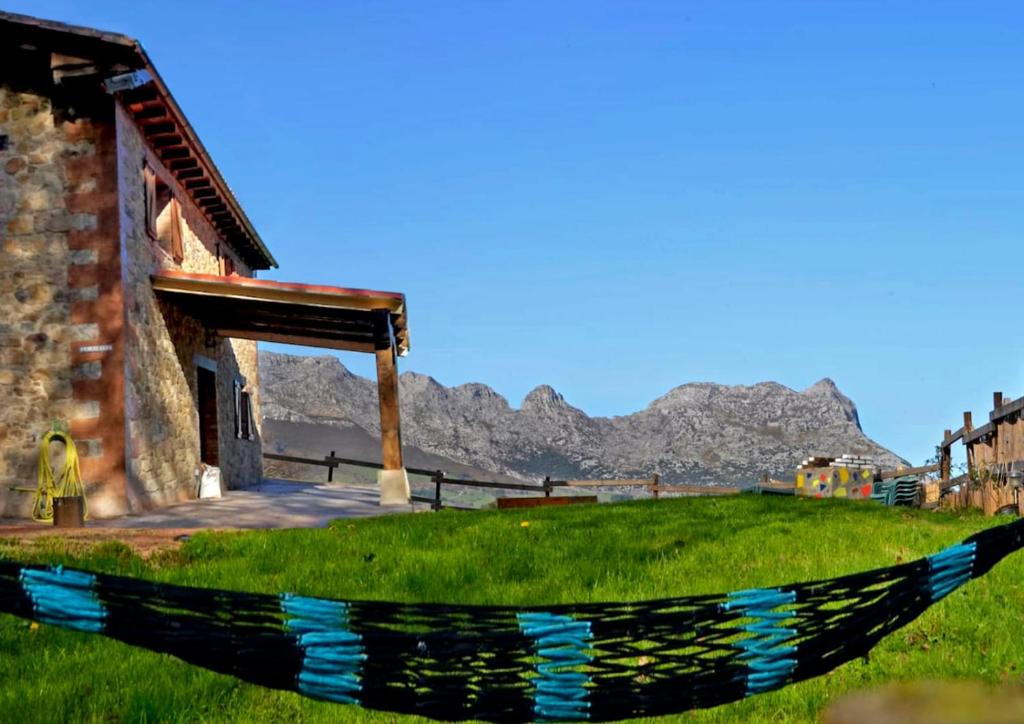 a hammock in front of a building with mountains in the background at La Cabaña de Naia in La Revilla