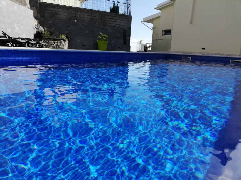 uma piscina com água azul em frente a um edifício em Imaculado Village em Funchal