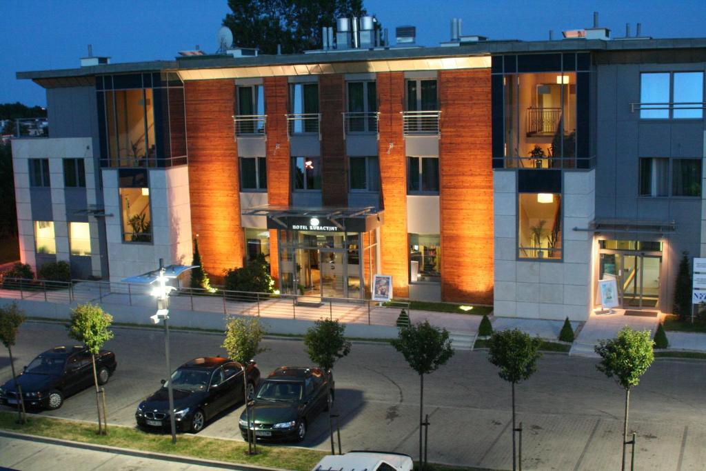 Hotel Kuracyjny Spa & Wellness في غدينيا: مبنى فيه سيارات متوقفة في موقف للسيارات