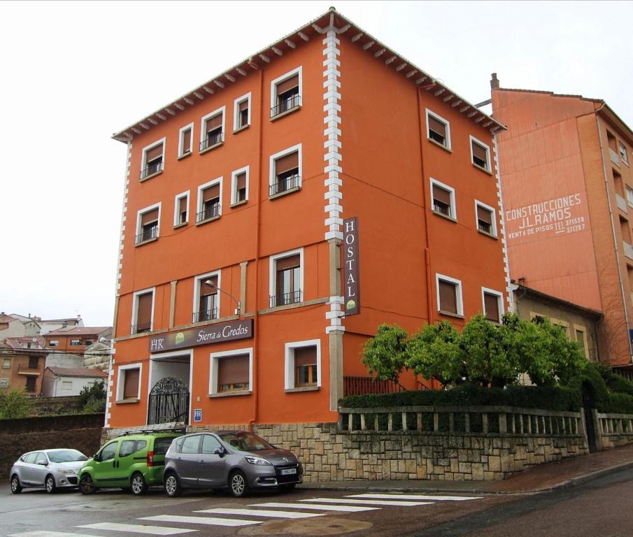 een oranje gebouw met auto's ervoor geparkeerd bij Hostal Sierra de Gredos in Arenas de San Pedro