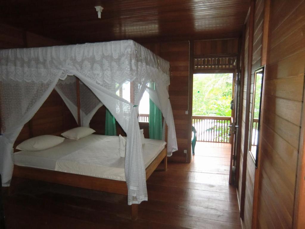 une chambre avec un lit à baldaquin dans l'établissement Bunaken Sea Garden Resort, à Bunaken
