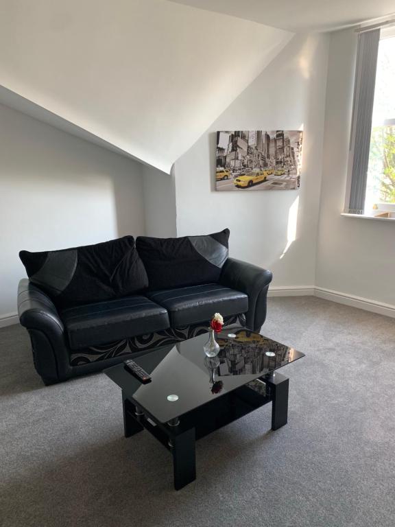 a living room with a black couch and a coffee table at No 9 - LARGE 1 BED NEAR SEFTON PARK AND LARK LANE in Liverpool