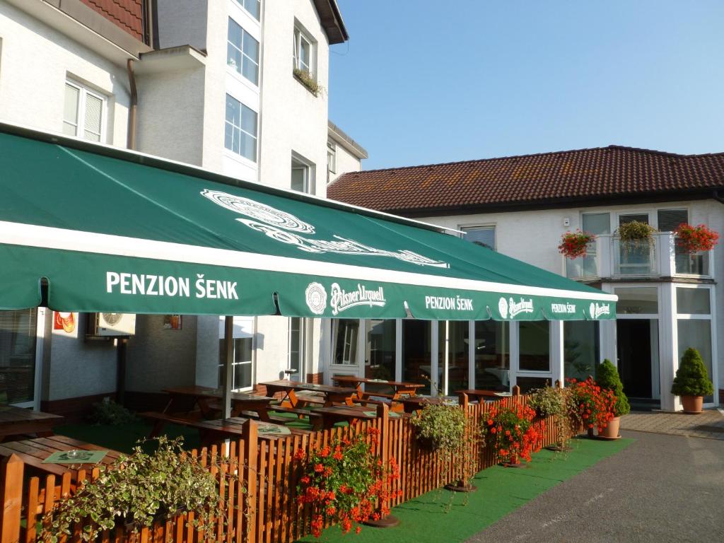 un restaurant avec un parasol vert, des tables et des fleurs dans l'établissement Penzion Šenk Pardubice, à Pardubice