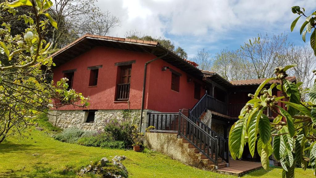 una casa roja con una escalera delante de ella en Amaicha Apartamentos Rurales en Ribadesella