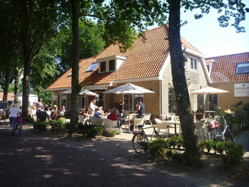 un groupe de personnes assises dans un restaurant sous des parasols dans l'établissement Hotelsuites Ambrosijn, à Schiermonnikoog