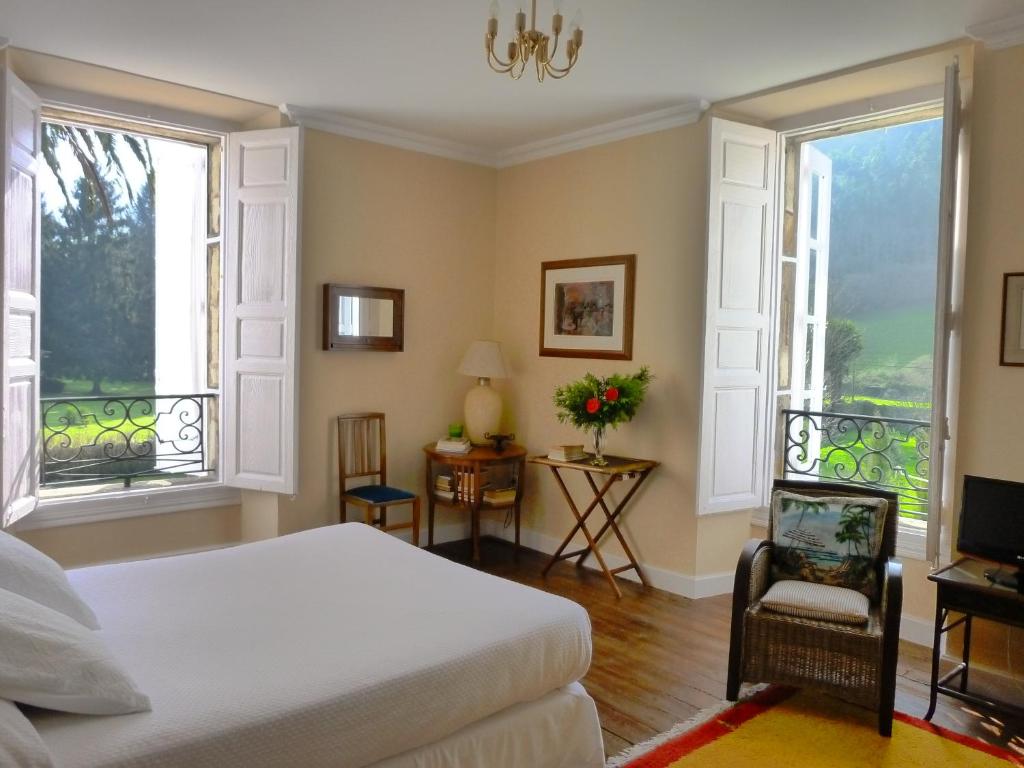 Un dormitorio con una cama y dos ventanas. en La Casona Azul, espectacular palacio indiano, en Corvera