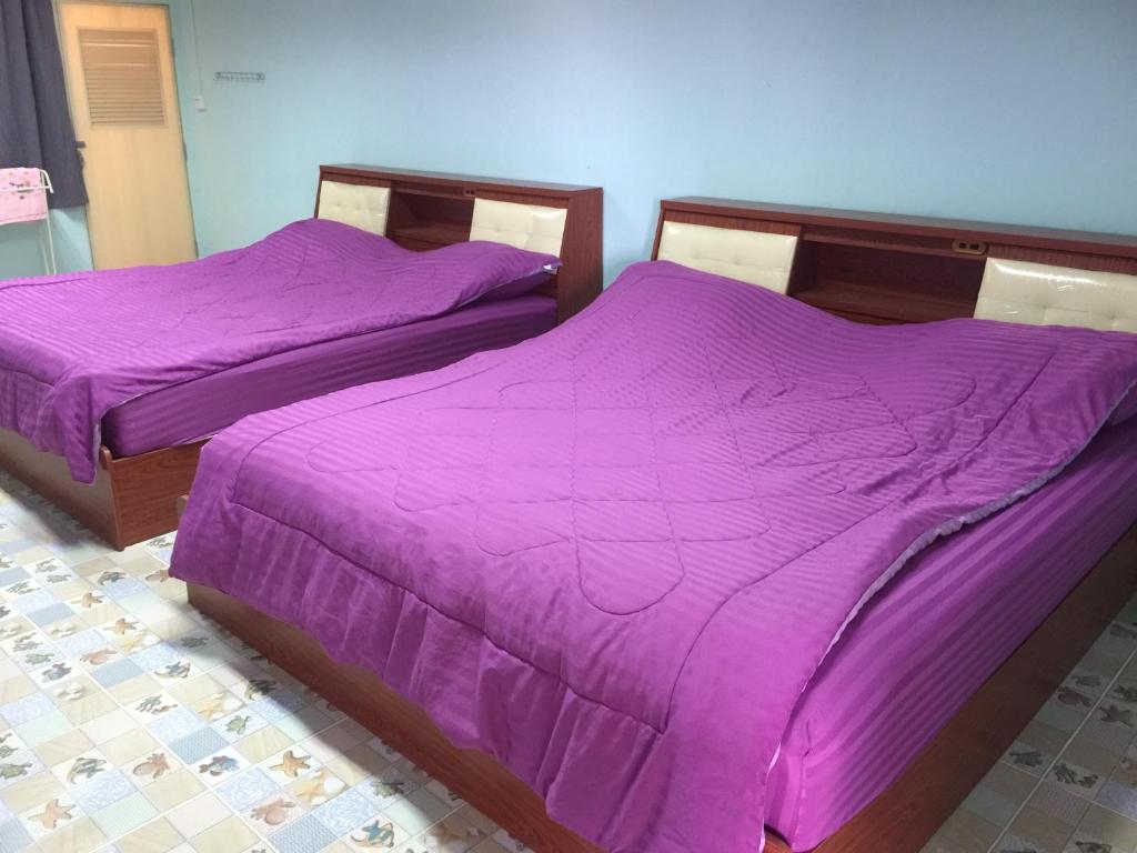 two beds with purple sheets in a room at Navy Home Sattahib in Sattahip