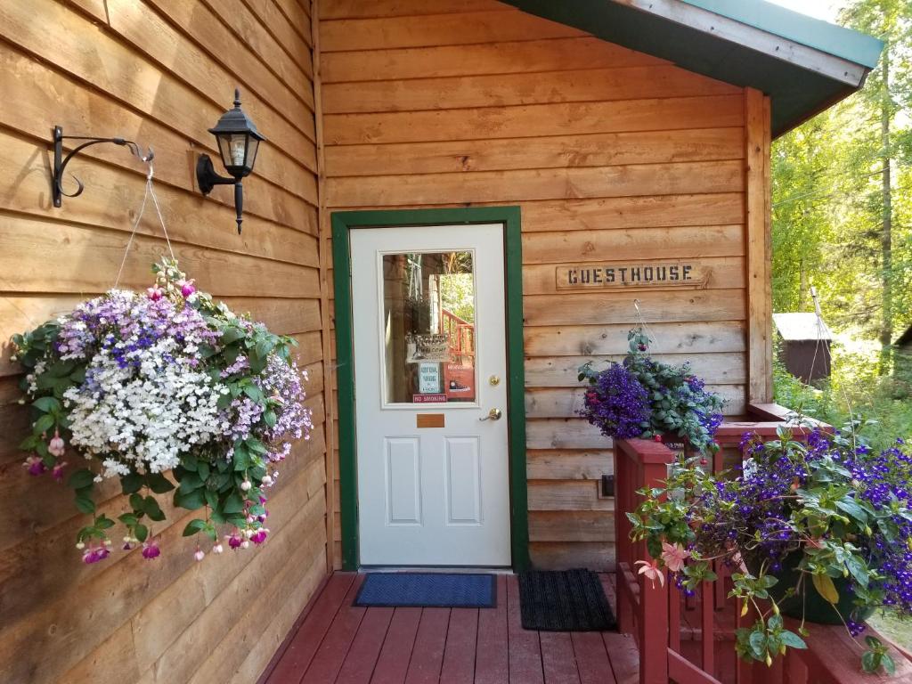 a front door of a wooden house with flowers at Talkeetna Hideaway in Talkeetna