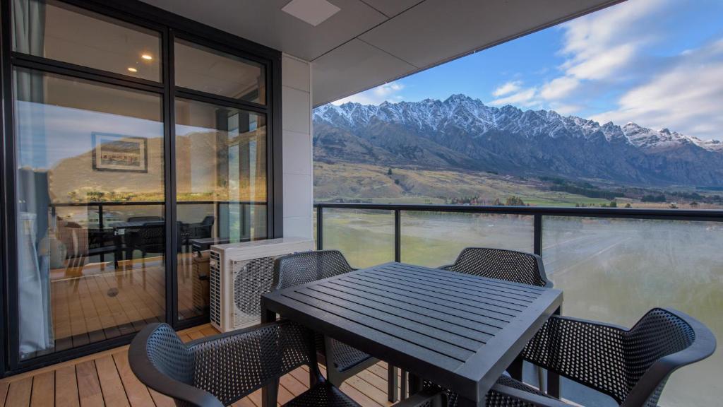 a table and chairs on a balcony with a view of mountains at Remarkables Garden 406 - Top Corner Unit - Super Convenient in Queenstown