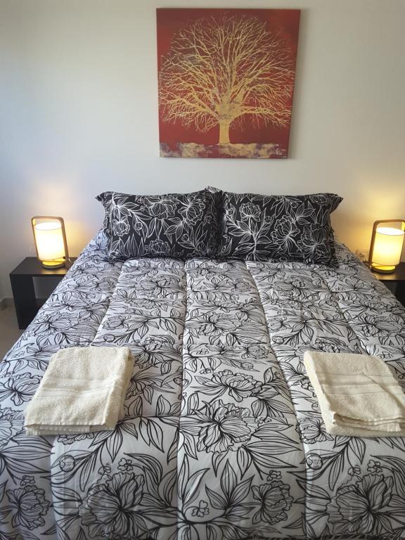 a bed with a black and white bedspread and two lamps at Esmeralda y Av Córdoba Microcentro in Buenos Aires