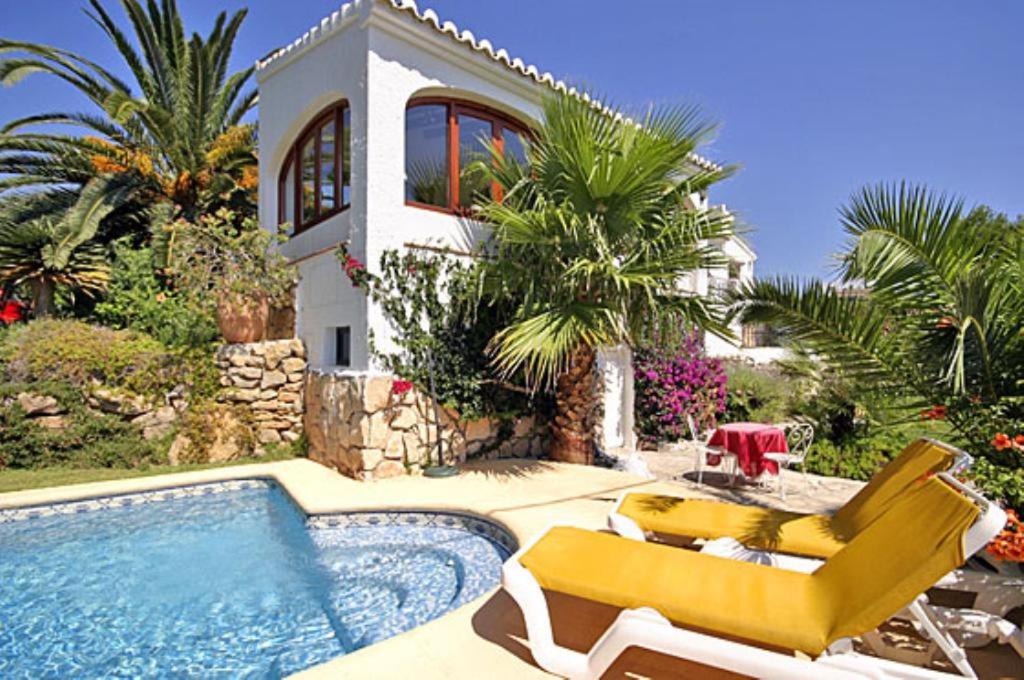 a villa with a swimming pool and two yellow chairs at Villa Maria in Jávea