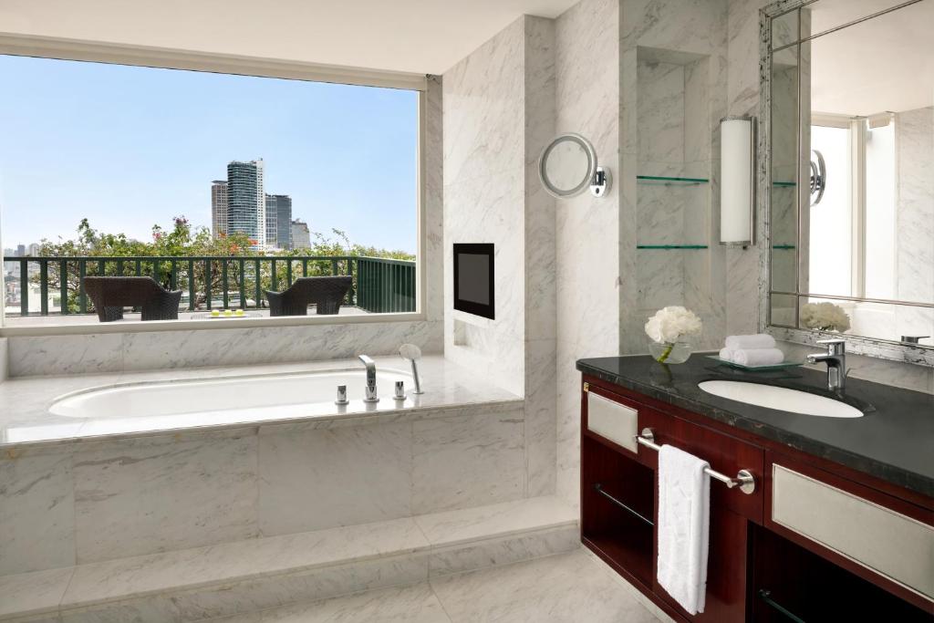 a bathroom with a tub and a sink and a window at Shangri-La Jakarta in Jakarta