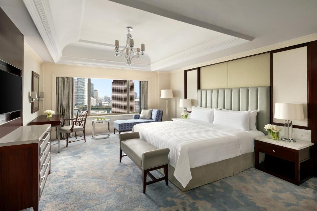 a bedroom with a large bed and a living room at Shangri-La Jakarta in Jakarta
