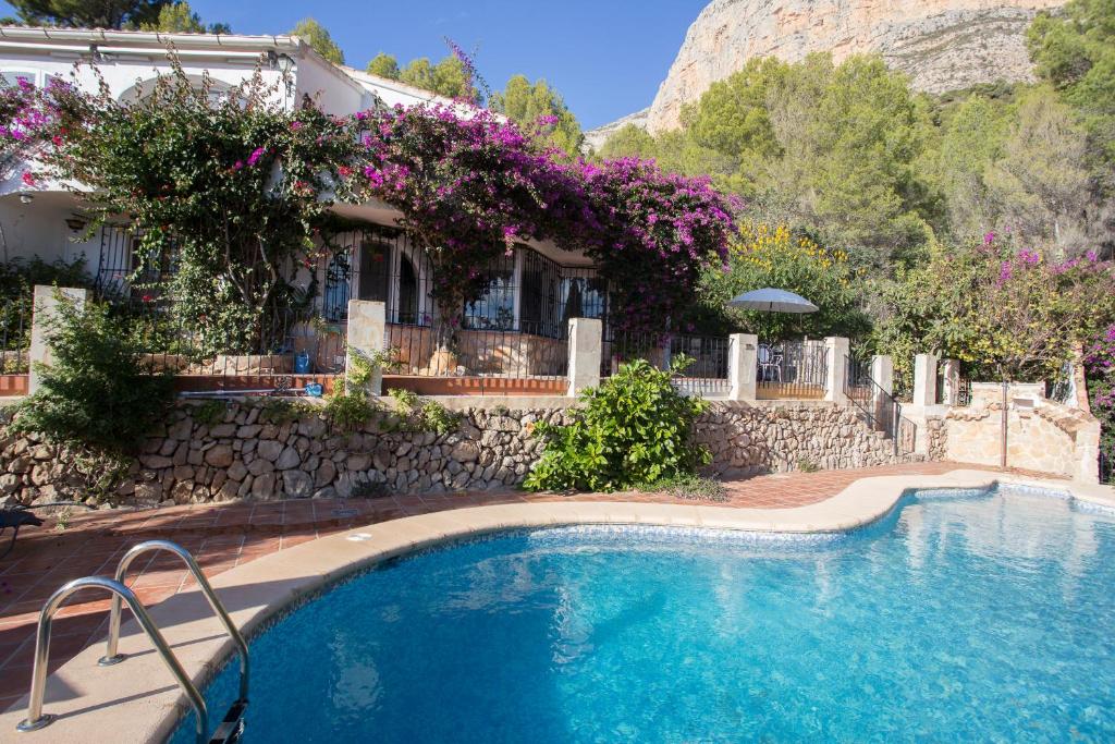 una piscina di fronte a una casa con fiori di Casa Nana a Jávea