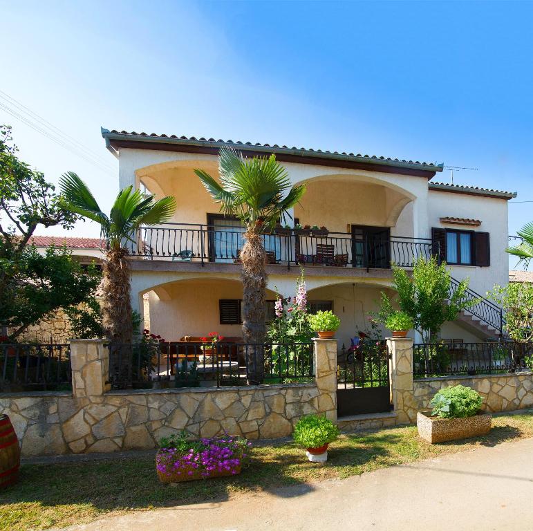 una casa grande con palmeras delante en Apartments Fabich, en Veleniki