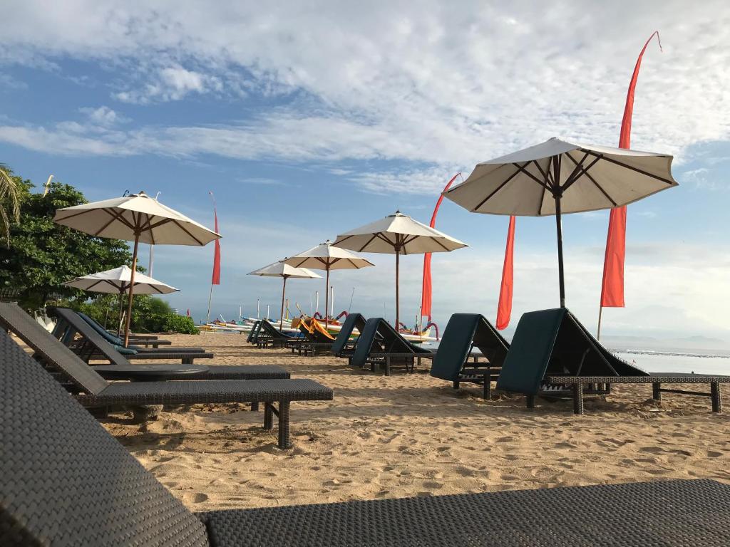 un grupo de sillas y sombrillas en una playa en Besakih Beach Hotel, en Sanur