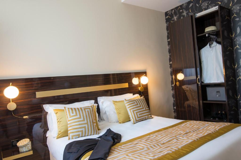 a bedroom with a large bed with yellow and white pillows at Hotel Carlton in Beaulieu-sur-Mer