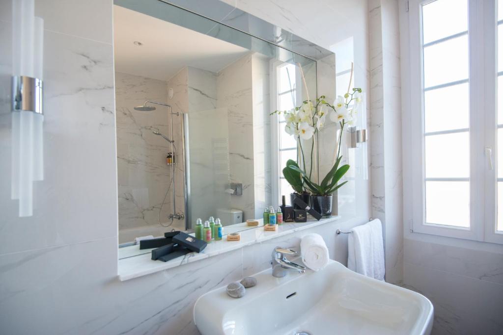 a white bathroom with a sink and a mirror at Hotel Carlton in Beaulieu-sur-Mer
