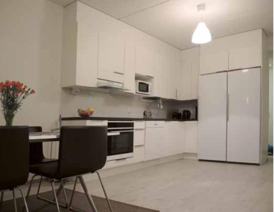 a kitchen with white cabinets and a table and chairs at Pearl in Raahe