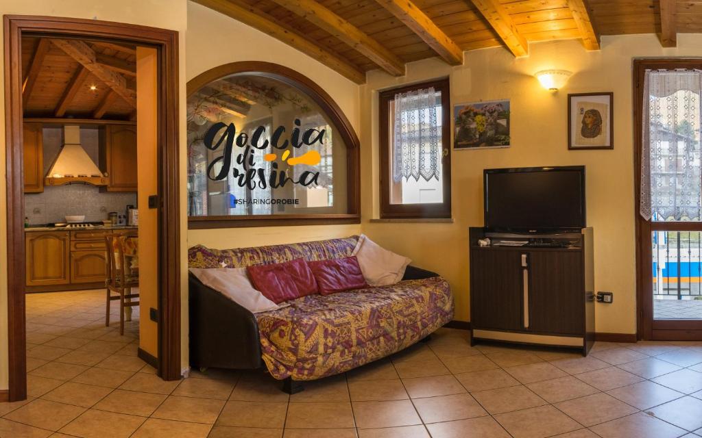 ein Wohnzimmer mit einem Sofa und einem TV in der Unterkunft Goccia di Resina #Sharingorobie in Serina