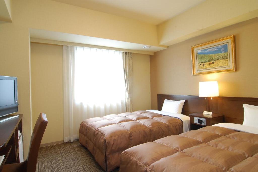 塩尻市にあるホテルルートイン塩尻のベッド2台と窓が備わるホテルルームです。