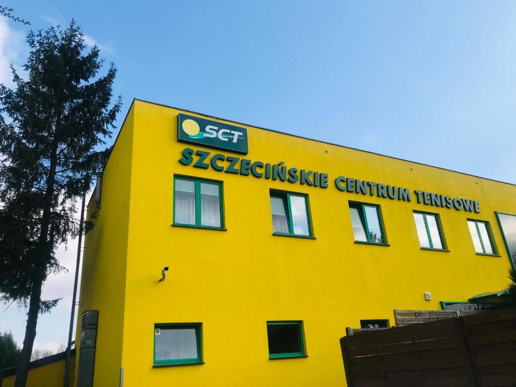 ein gelbes Gebäude mit einem Schild an der Seite in der Unterkunft Szczecińskie Centrum Tenisowe in Stettin
