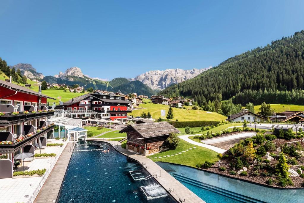 arial view of a resort with a river and mountains at Hotel Alpenroyal - The Leading Hotels of the World in Selva di Val Gardena
