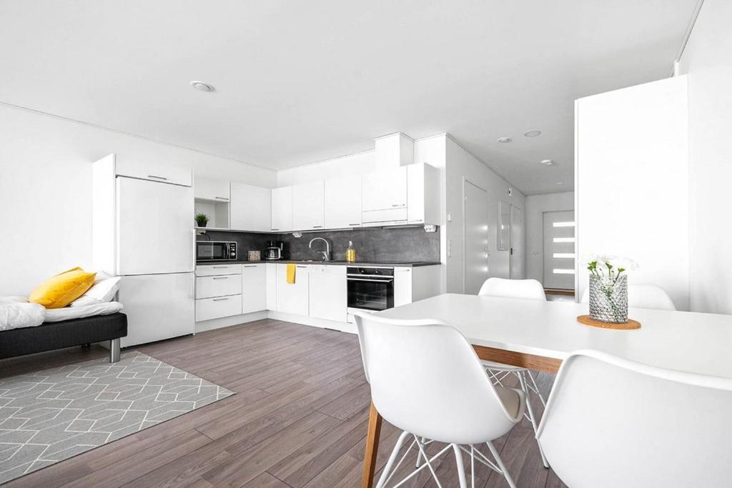 a kitchen with white cabinets and a table and chairs at Hämeentie Apartments in Järvenpää