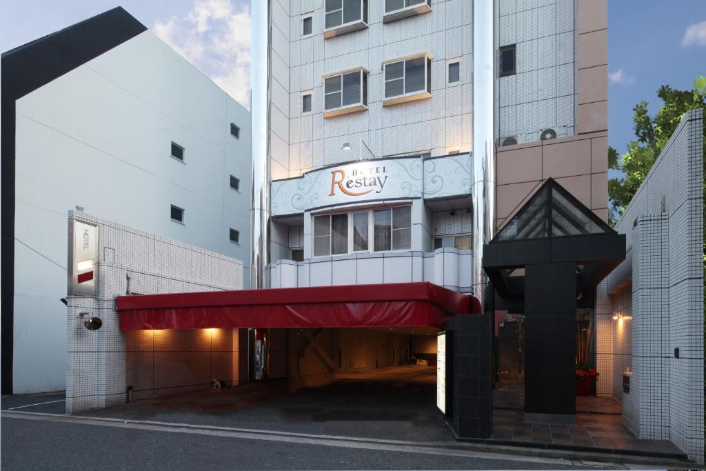 ein Hotel mit einer roten Markise vor einem Gebäude in der Unterkunft Restay Hiroshima (Adult Only) in Hiroshima