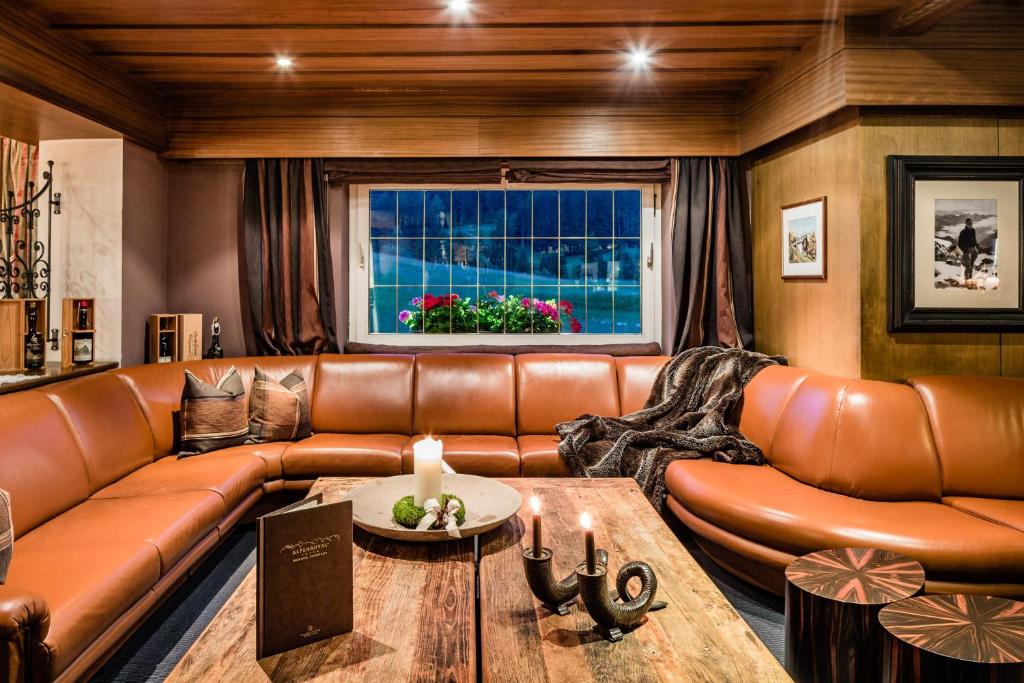 a living room with a leather couch and a table at Hotel Alpenroyal - The Leading Hotels of the World in Selva di Val Gardena