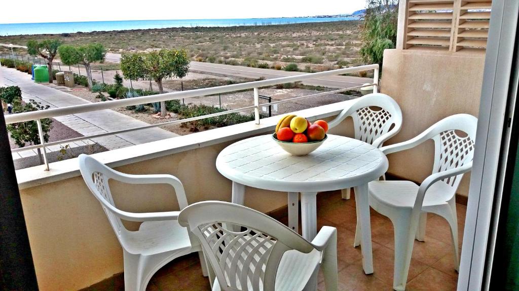 Apartamento Tania - El Toyo - Cabo de Gata في ريتامار: طاولة وكراسي على شرفة مع وعاء من الفواكه