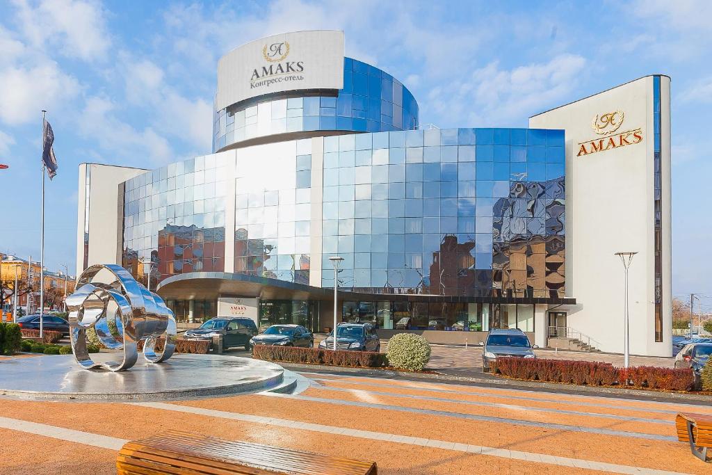 a large glass building with a sculpture in front of it at AMAKS Congress Hotel in Ryazan