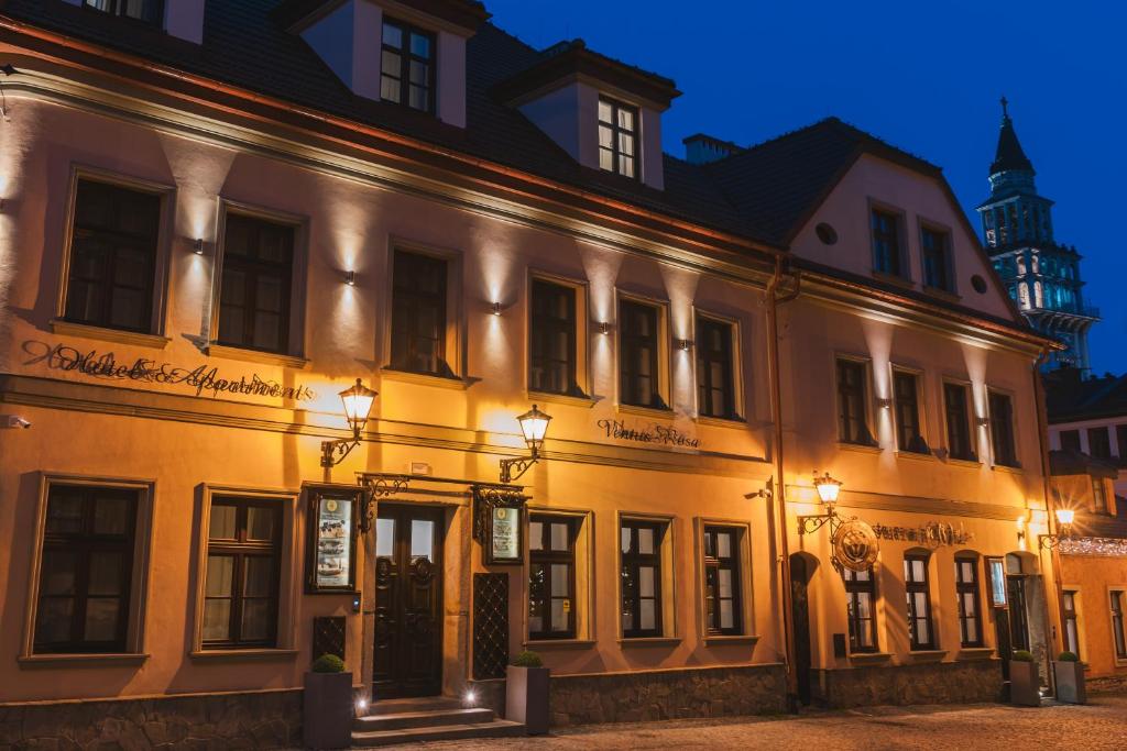 a large white building at night at Hotel & Apartments Ventus Rosa in Bielsko-Biała