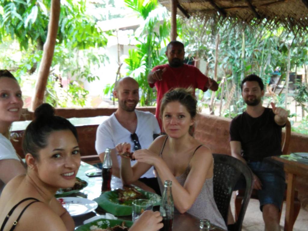 eine Gruppe von Menschen, die in einem Restaurant an einem Tisch sitzen in der Unterkunft Gimanhala Cottage & Cookary Class in Anuradhapura