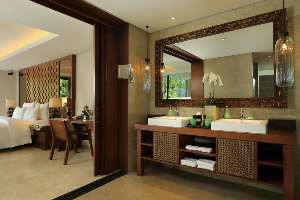 a bathroom with two sinks and a bedroom with a bed at Anantara Uluwatu Bali Resort in Uluwatu