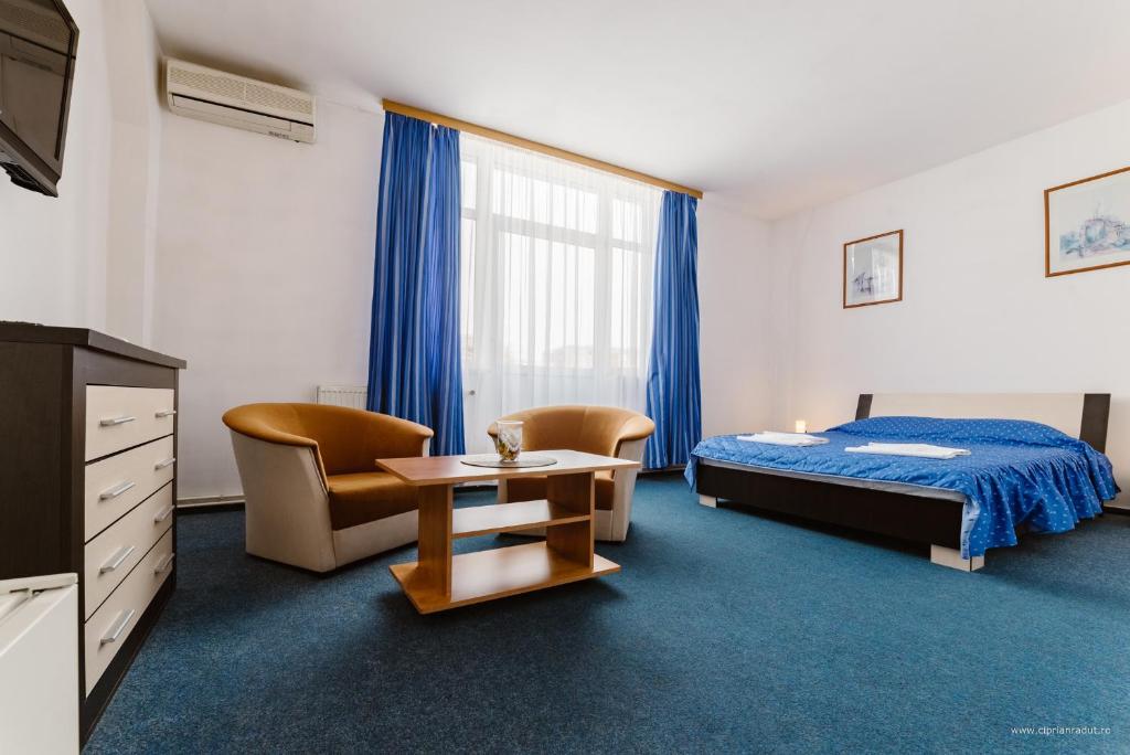 a hotel room with a bed and a table and chairs at Hotel Iris in Tîrnăveni