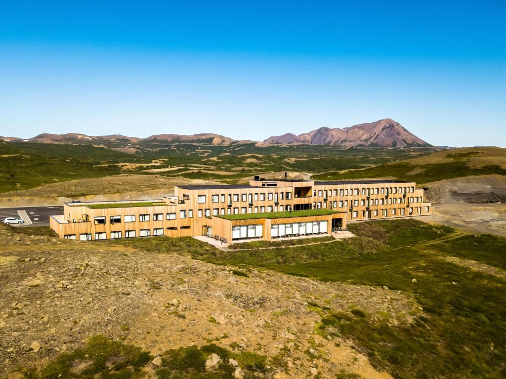 a building on a hill with mountains in the background at Fosshótel Mývatn in Myvatn