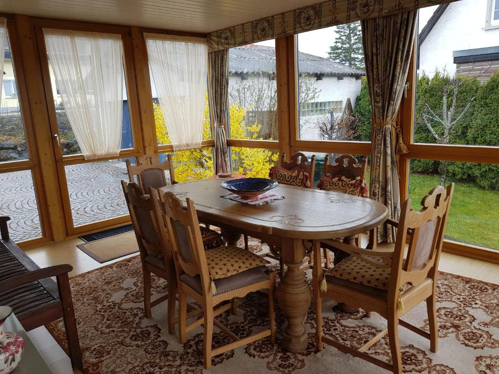 uma sala de jantar com mesa, cadeiras e janelas em Ferienwohnung Moni em Bräunlingen