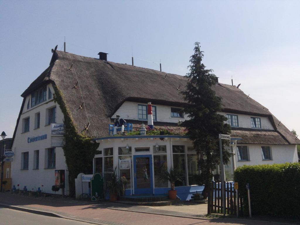 un ancien bâtiment blanc avec un toit de chaume dans l'établissement Landhotel Ostseetraum & Fewo, à Warnemünde