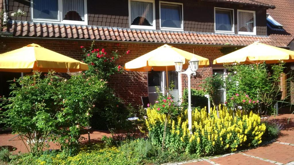 two umbrellas and flowers in front of a building at Gästehaus Bommelsen in Walsrode