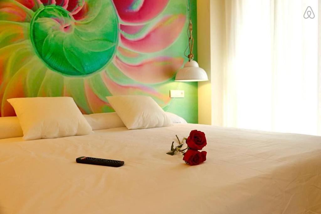 Una cama con control remoto y rosas rojas. en The Shell - New Apartment en Alicante