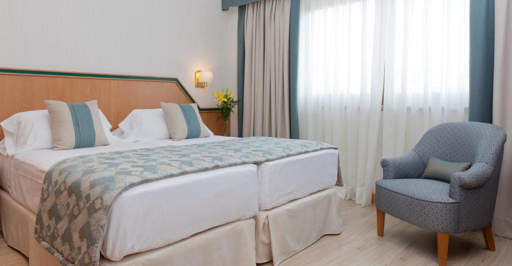 - une chambre avec un grand lit et une chaise dans l'établissement Hotel Praga, à Madrid