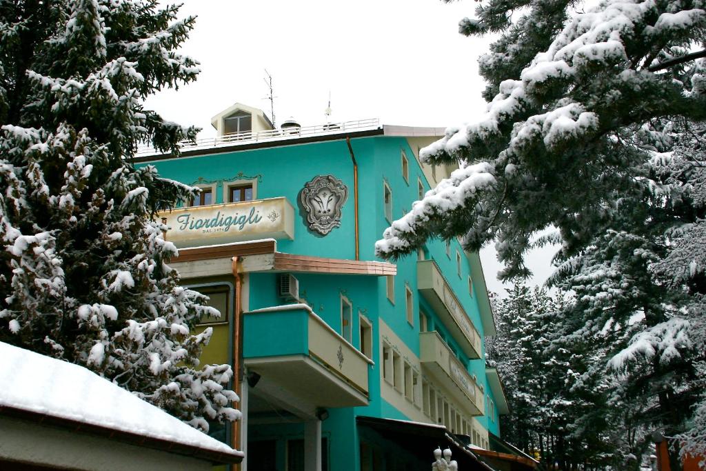 Un edificio blu con un orologio sulla neve di Hotel Fiordigigli ad Assergi