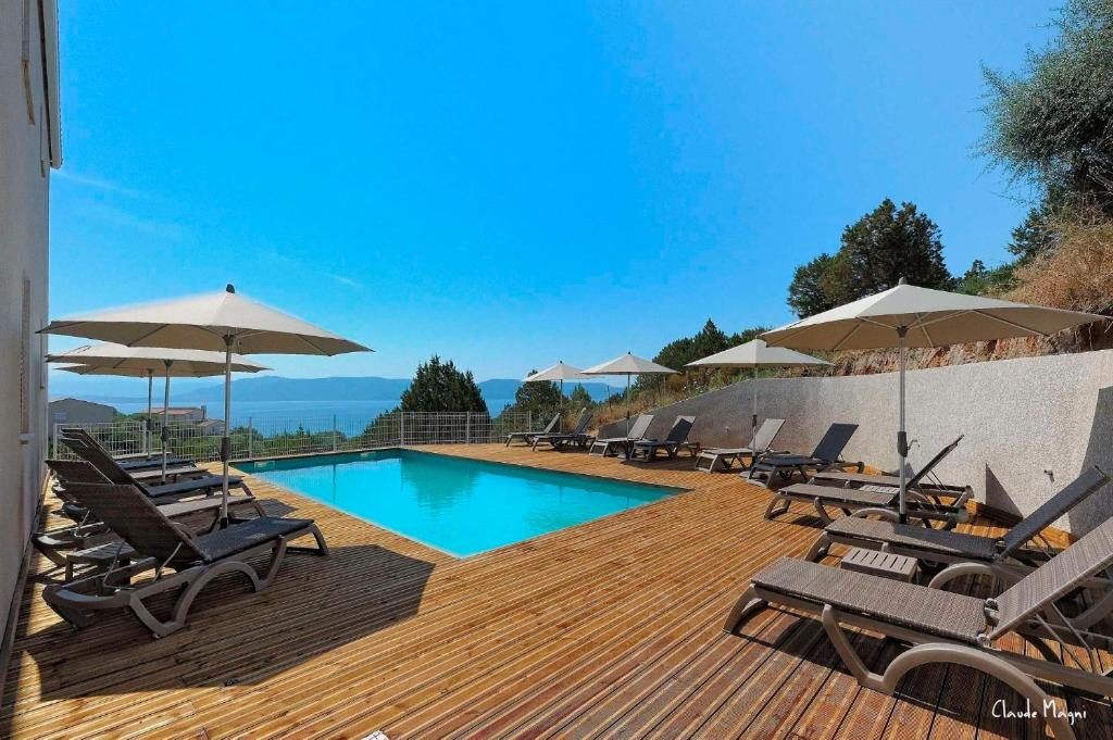 a pool with chairs and umbrellas on a wooden deck at Résidence Giovanello in Porto Pollo