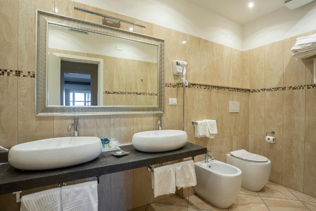 a bathroom with two sinks and a mirror and a toilet at Hotel Rex in Livorno